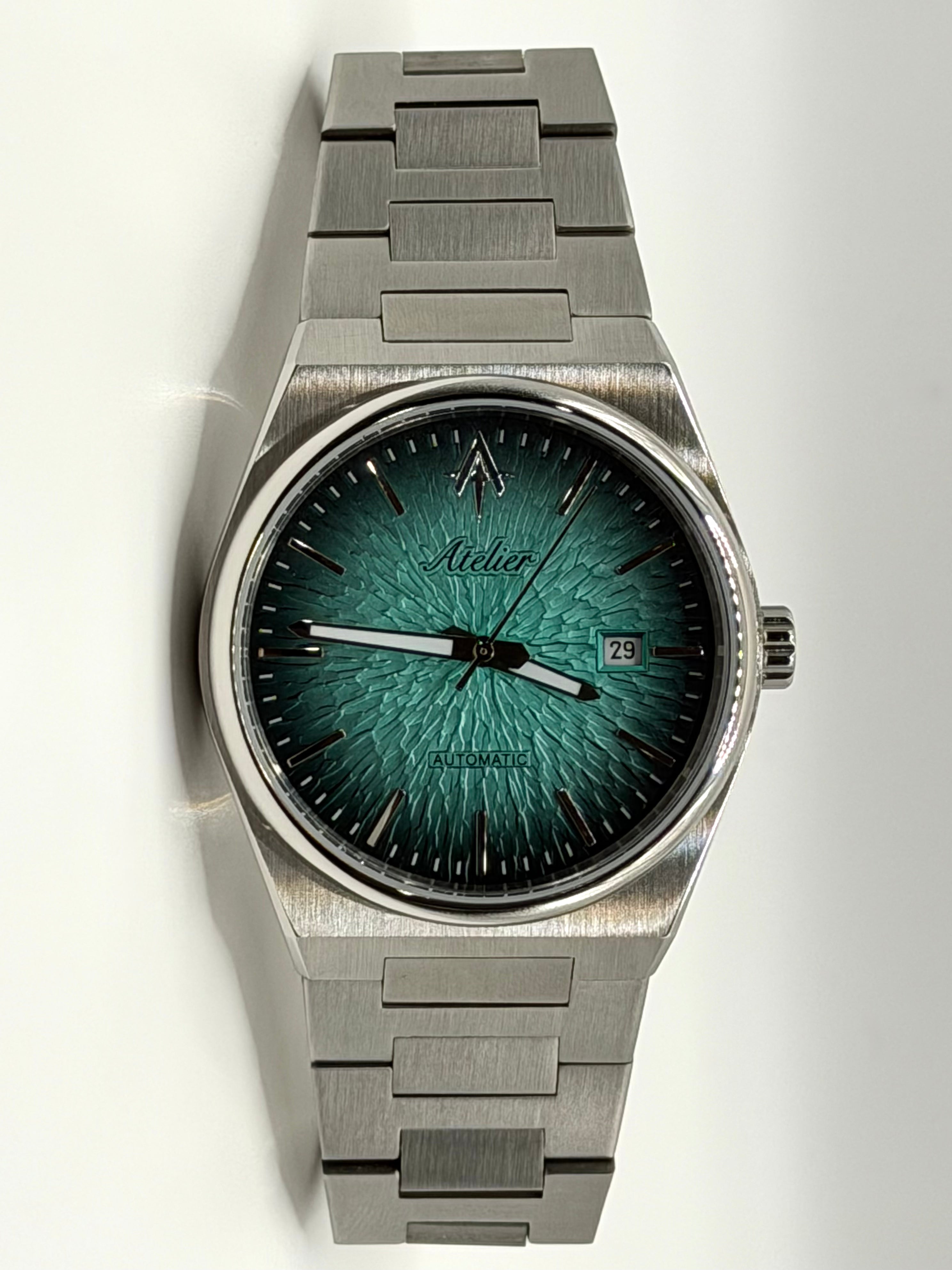 A stainless steel wristwatch with a textured tiffany blue dial, silver hands and markers, and a matching brushed steel link bracelet, shown against a plain white background.